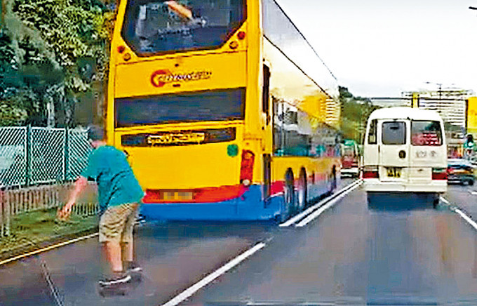青年踩电动滑板尾随巴士行驶，险象环生。