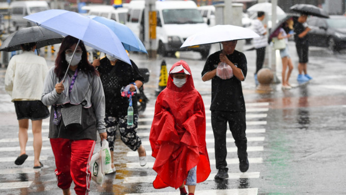 在北京市朝阳区行人冒雨行走在路上。新华社
