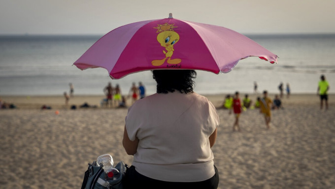 民众无不举伞遮太阳。美联社图片