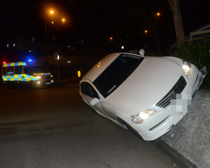 車身兩個車輪擱於花槽石壆上。