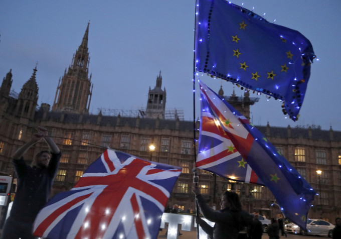 英國國會投票決定脫歐的替代方案，有示威者在倫敦議會大廈外揮舞著旗幟抗議。AP
