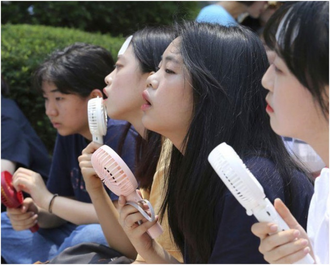 南韓持續極端酷熱天氣，中學生手持風扇解暑。