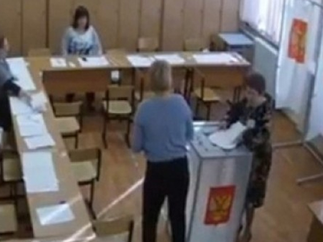 一名选举职员被拍到，手持一叠已填好的选票放入投票箱内。 影片截图