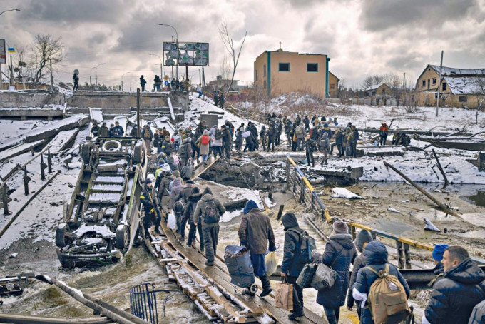 在乌克兰首都基辅郊区伊尔平，逃难的民众渡过一座损毁的桥梁。  