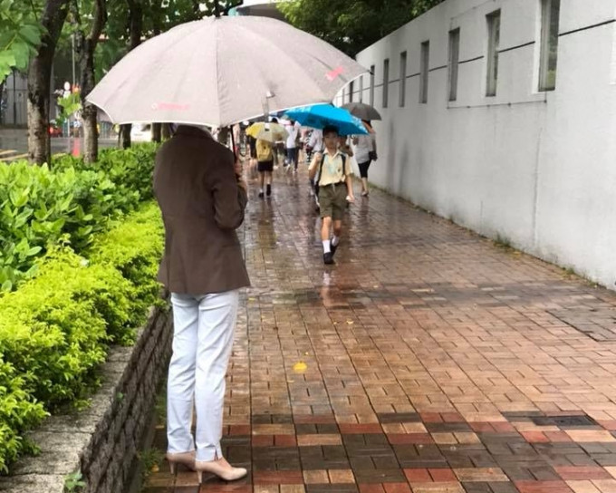 小学校长撑伞为母子挡雨。Moon Choo图片