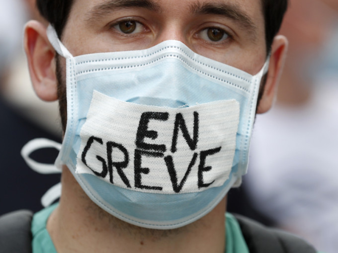 示威者在口罩上写上罢工，他们要求改善医护人员的薪金，以及对公立医院投放更多资源。AP图