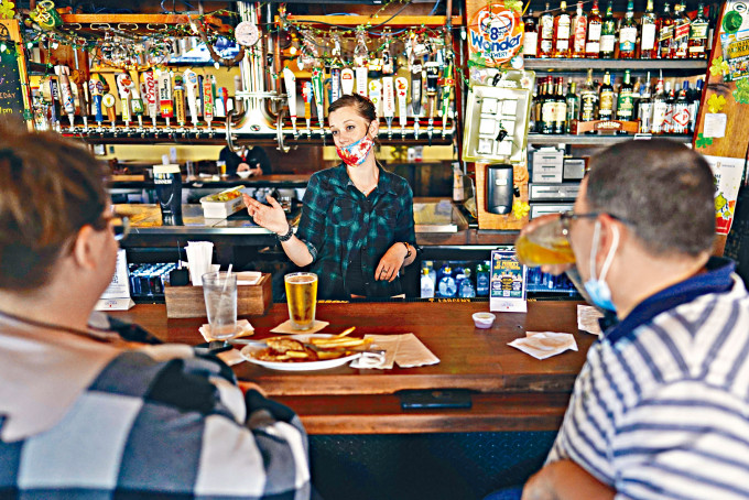休斯敦一家酒吧的酒保周二半戴口罩与顾客聊天。