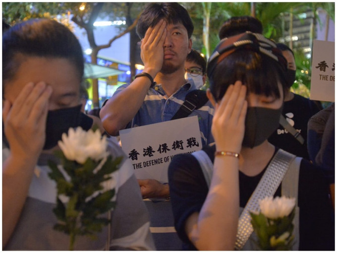 集会人士遮掩右眼向女示威者致意。