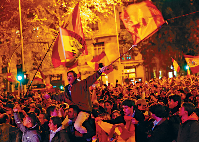 西班牙马德里大批民众周二到工人社会党总部附近示威，期间有示威者挥动国旗。
