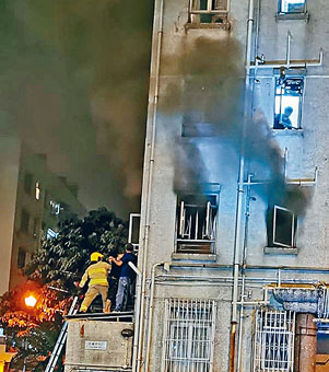 ■起火单位窗口冒烟，消防员在檐篷协助救人。