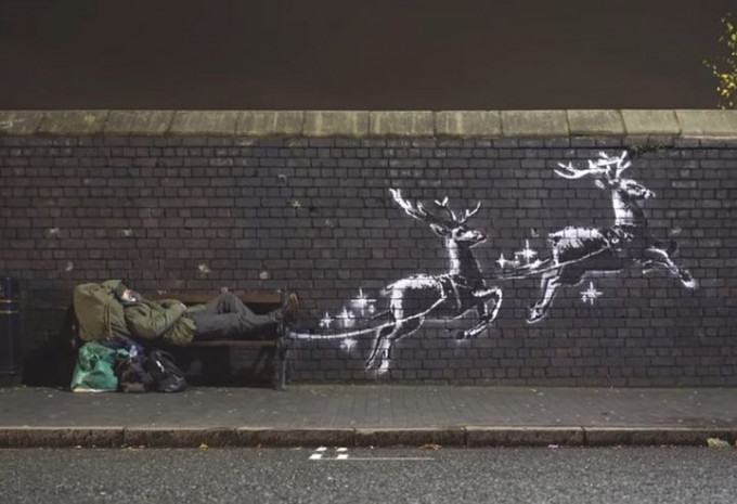 圖為塗鴉大師班克西的最新作品，他畫上兩隻馴鹿載着躺臥在長椅的流浪漢飛天。（Banksy Instagram）