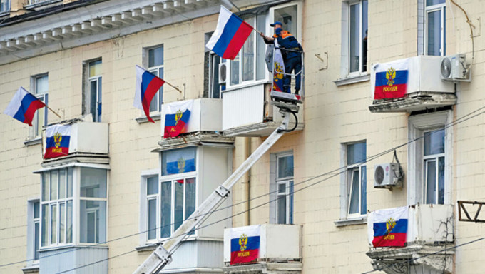 在乌克兰东部卢甘斯克，周二有工人在住宅大厦挂起俄罗斯国旗。AP