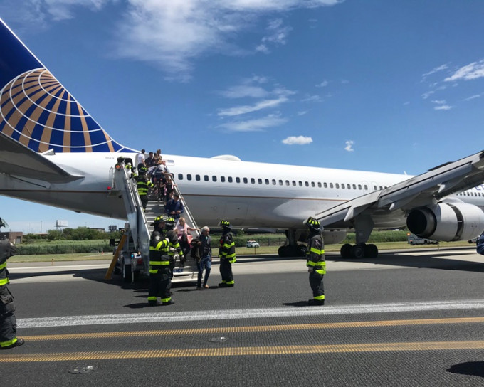 消防员到场帮助乘客离开客机。AP