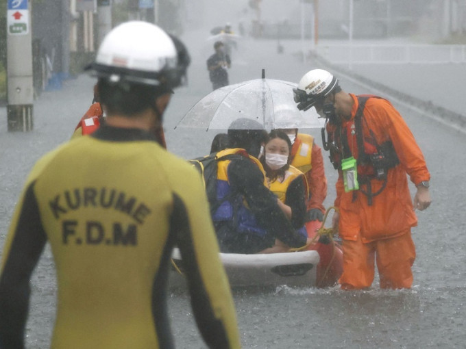 福冈县久留米大雨淹没马路消防队员协助居民疏散。REUTERS