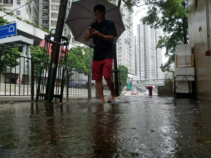 途人在香港仔中心外行人路涧水而行。