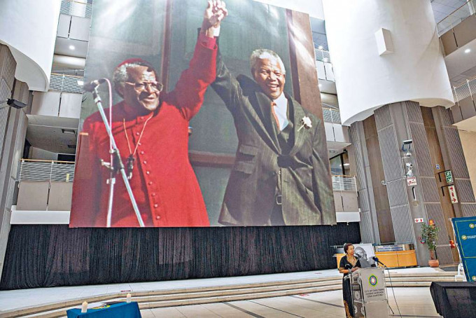 ■開普敦市周日開記者會談圖圖逝世，背景是圖圖（左）與前總統曼德拉的照片。