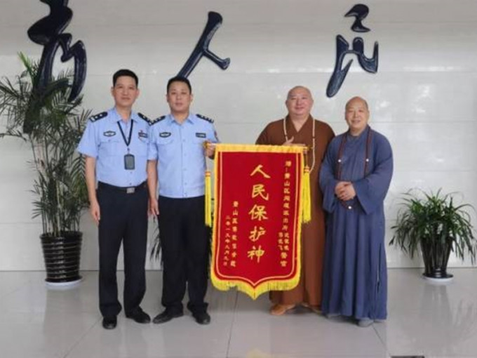 两位身穿袈裟的大师送上写有「人民保护神」的锦旗感谢警员破案。 网图