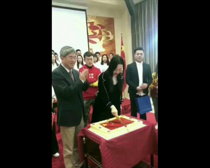 一名女子切开印有五星红旗图案的蛋糕。网图