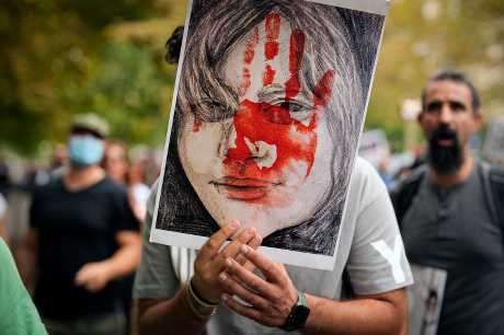  在羅馬尼亞布加勒斯特市，一名男子周六參加對伊朗庫爾德族女子阿米尼(Mahsa Amini)之死表達抗議的活動期間舉起卡牌。AP圖片