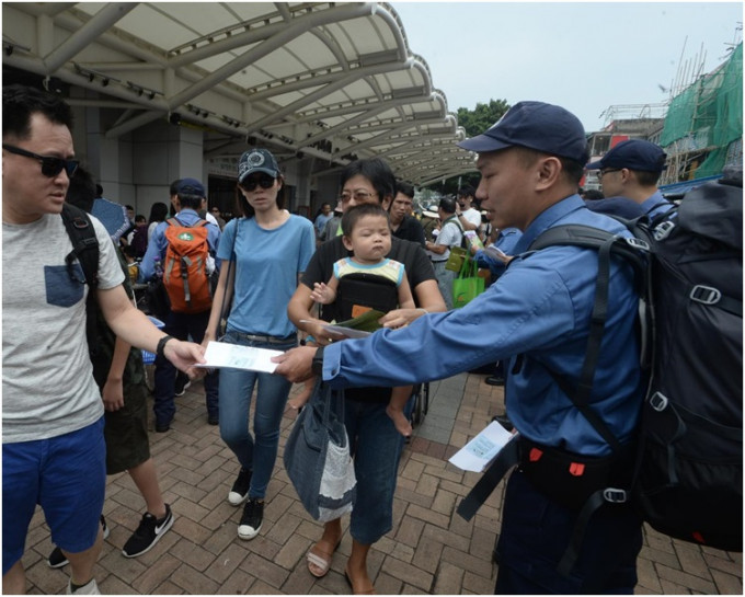 民安隊員在碼頭向居民及遊人派滅蚊宣傳單。