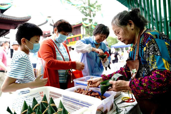 遊客在上海召稼樓古鎮一攤位學包粽子。 新華社圖片