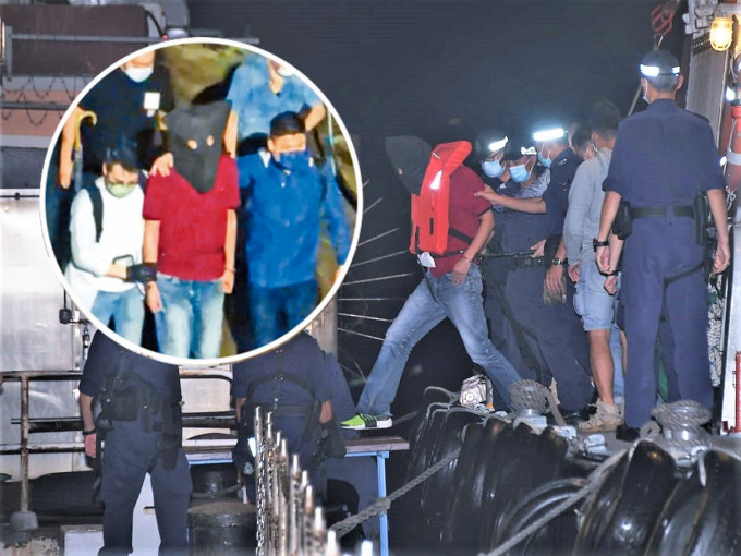 身穿红衣的疑凶蔡南生，昨晚在南丫岛落网后由多名人员押走。