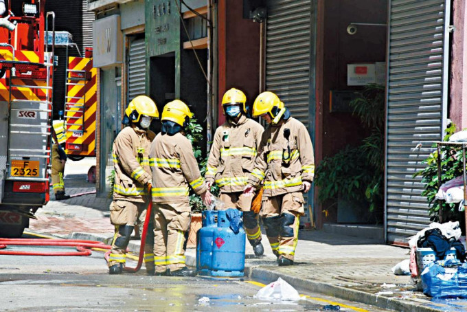 消防员在洗衣店内搬出肇事的石油气樽检查。