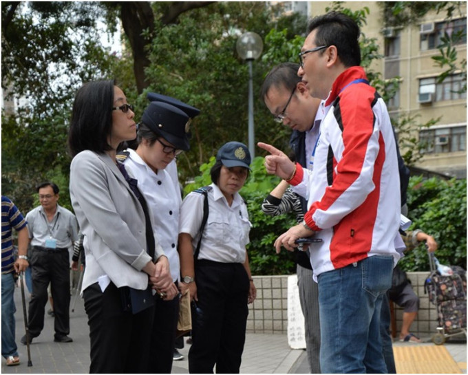 李东江(右)与食环署职员巡视宿舍附近地方要求加强清洁。