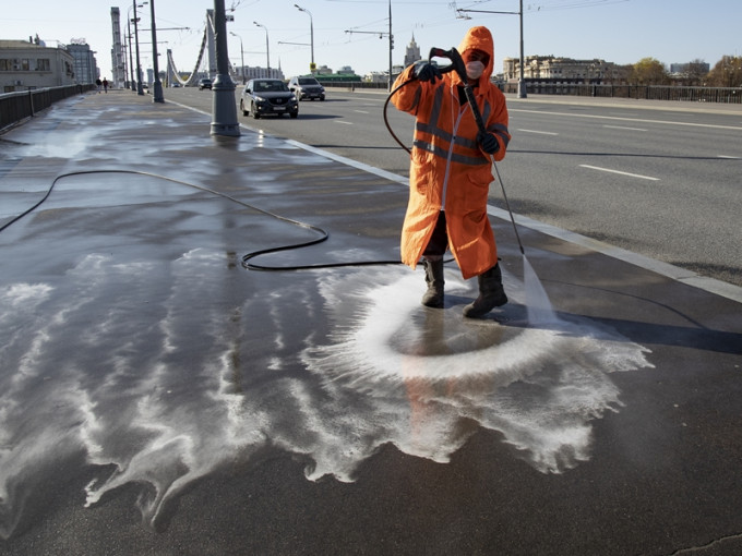 俄羅斯莫斯科一名清潔工身穿防護衣消毒街道。 AP