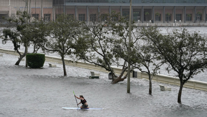 民众在坦帕市中心沿着被水淹没的海湾大道划滑浪板。 美联社