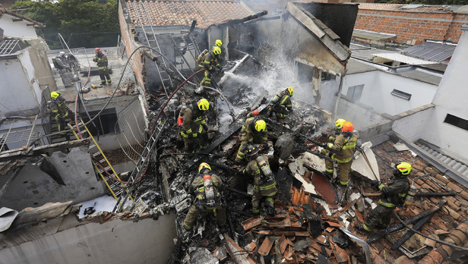 小型飞机坠落哥伦比亚民宅起火，消防到场开喉灌救。AP