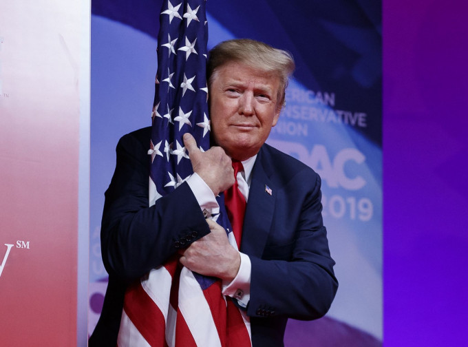 特朗普步入講台致詞時顯得非常興奮，甚至一臉陶醉地擁着一面美國國旗。AP