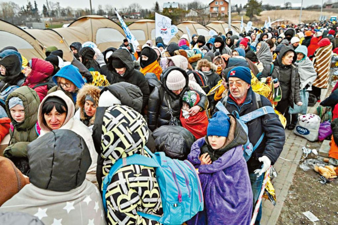 大批進入波蘭的烏克蘭難民，在嚴寒下排隊等候轉往一個火車站。　