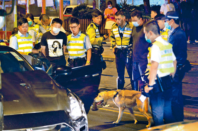 ■在警犬协助下，警方押同司机(左)及乘客(右)搜查车辆。
