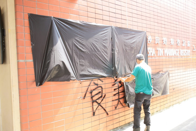 外墙遭人喷写字句涂鸦，职员用黑胶袋遮盖。杨伟亨摄