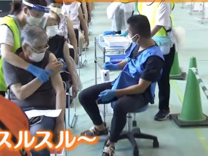 日本医生坐旋转滑轮椅为民众接种新冠疫苗，据称提高了8倍效率。（影片截图）