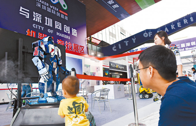 深圳從來料加工廠轉型為創新型城市。圖為大眾創業萬眾創新活動周上，一名兒童觀察一台準備展示的機器人。