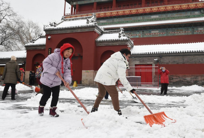 北京已发暴雪橙色预警，民众正清理道路积雪。新华社