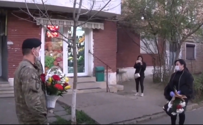 罗马尼亚医护遭邻居淋消毒水，士兵献花代致歉。影片截图
