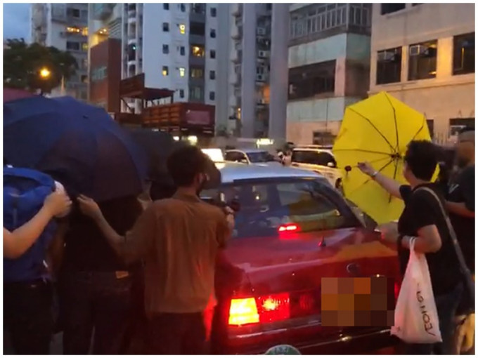 支持者撑伞保护被告上的士。