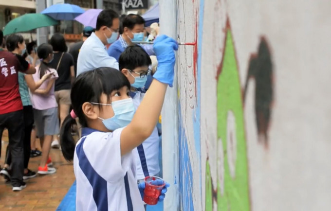 小孩专心地为西区警署墙壁上画有宣传道路安全的图画涂上颜色。
