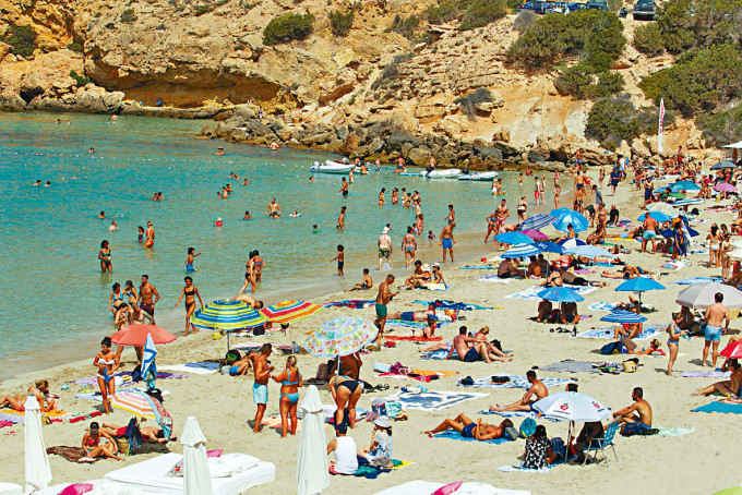 西班牙伊维萨岛上，大批泳客在海滩享受日光浴。