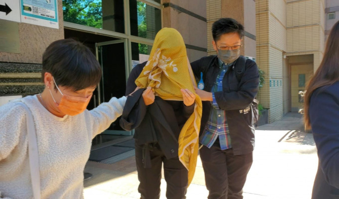 盖上头巾的被告获3人护送离开法院。陈晓欣摄