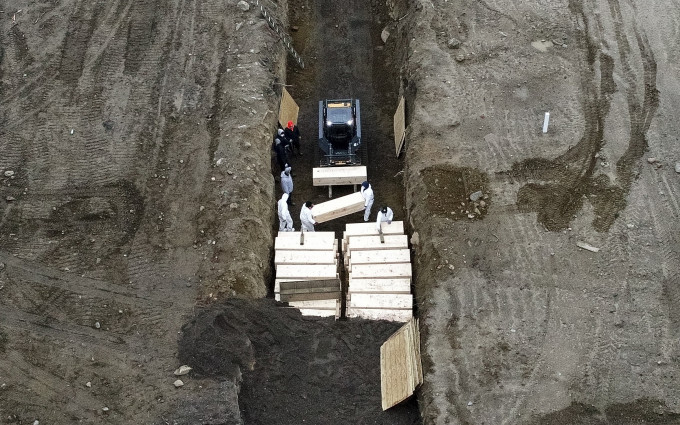 多名穿上防护衣的人员在岛上挖坑埋葬尸体。AP