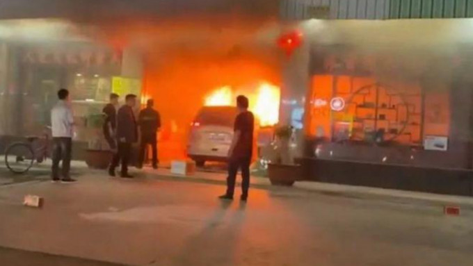 白色私家車撞入商店後迅即引發大火，周邊商店人員欲救無從。影片截圖