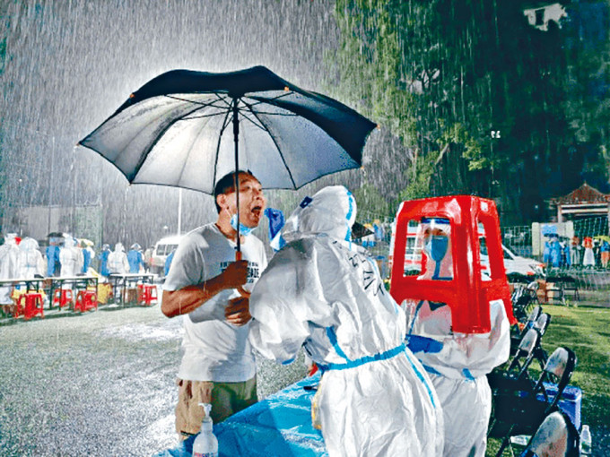 ■廣州民眾在暴雨中接受病毒檢測。