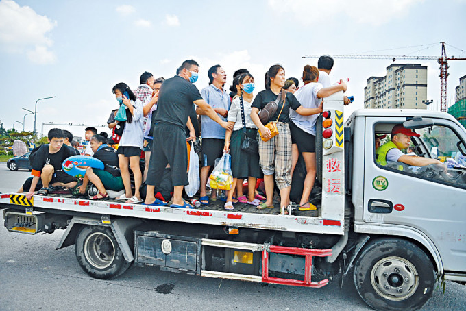 河南省衞輝市，民眾登上平板卡車，準備從市區轉移。