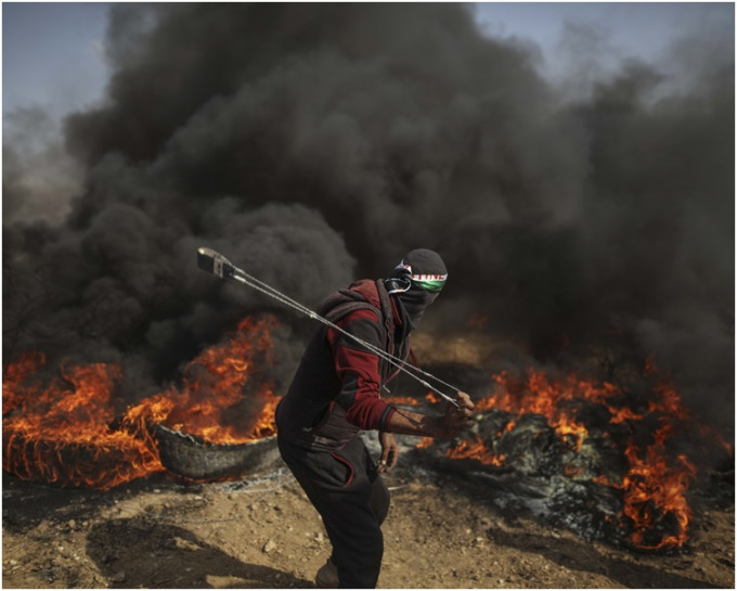 示威者揮舞巴勒斯坦旗幟和焚燒舊車胎。 新華社