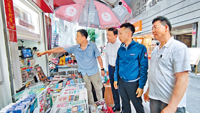 中西區滅罪委員會主席陳偉泉（左二）及王煒楠總督察（右二）向安裝閉路電視的商戶了解情況。