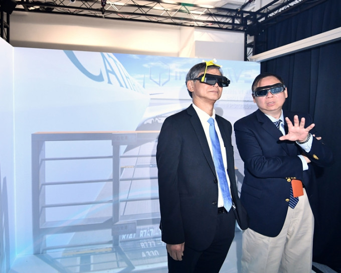 羅致光(左)和黃廣揚(右)試戴虛擬實境眼鏡，體驗有關機場設施運作的訓練。政府新聞處圖片